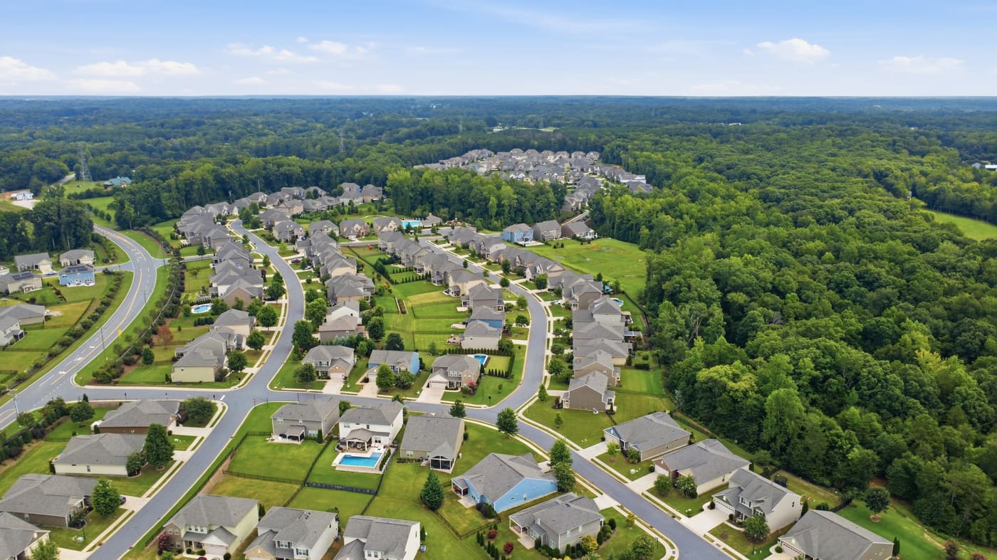 A wide aerial of the neighborhood set against continuous woodland.