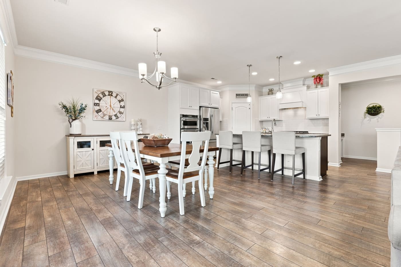 The dining area beneath a chandelier, open to the kitchen.