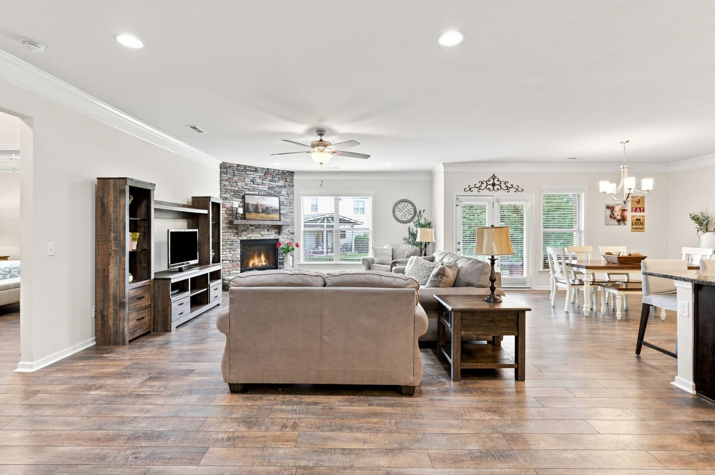 The family room looking toward the dining area, fire lit in the stacked-stone fireplace.