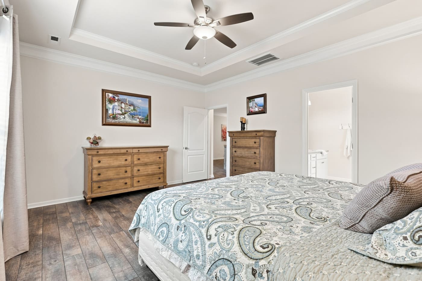 The primary bedroom looking toward the bath and closet entry, tray ceiling above.